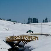 Snow-covered wooden bridge and stream in Gulmarg, Kashmir winter wonderland