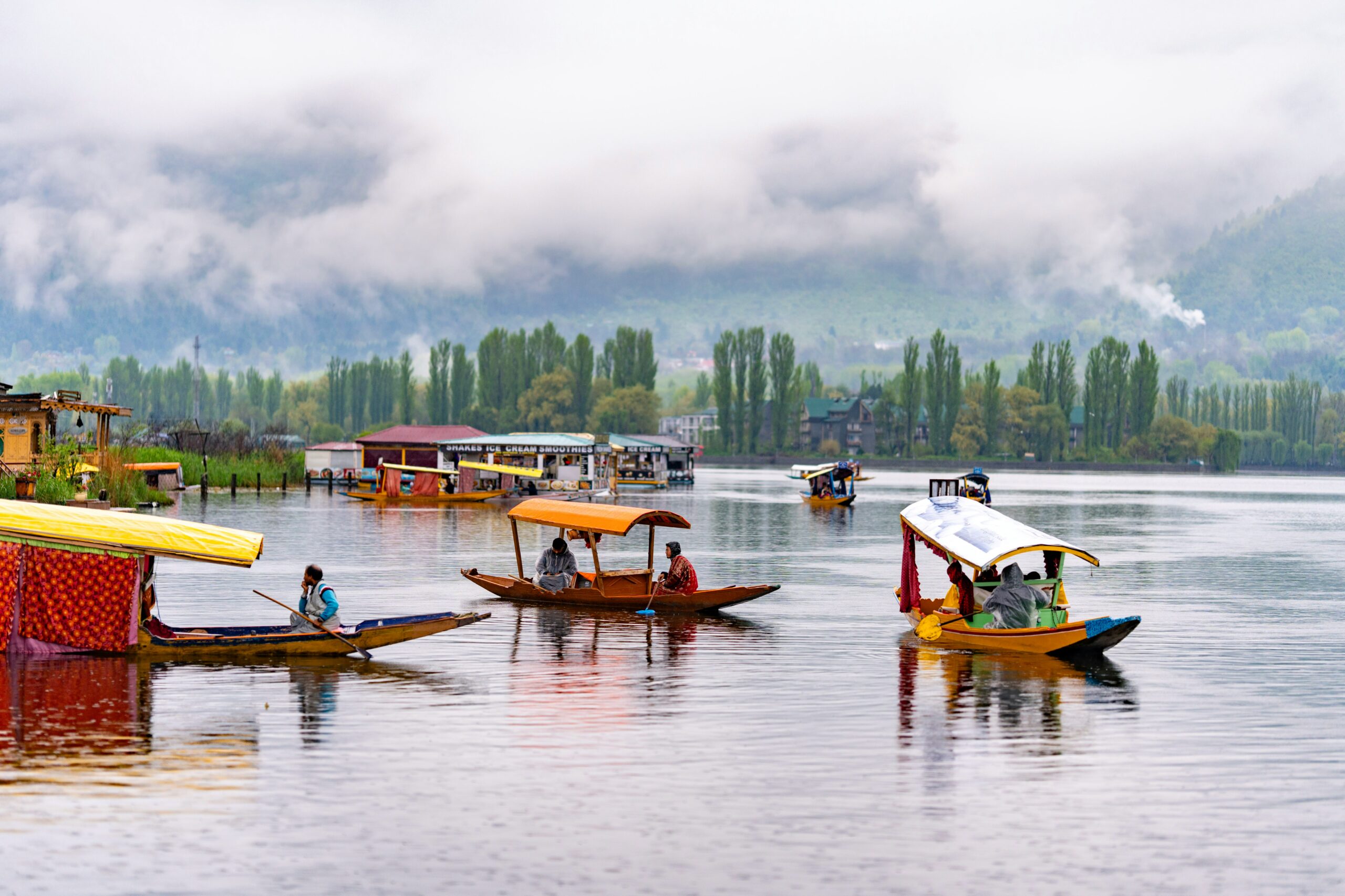 Colorful shikaras and houseboat floating on Dal Lake with mountains in Srinagar, Kashmir