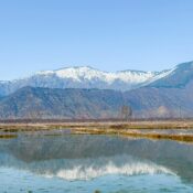 Scenic view of Kashmir valley with snow-capped mountains and reflective lake