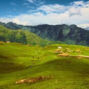 Lush green valley with mountains in Kashmir representing sustainable travel.