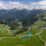 Gulmarg landscape with green meadows, forested slopes and snowy mountains