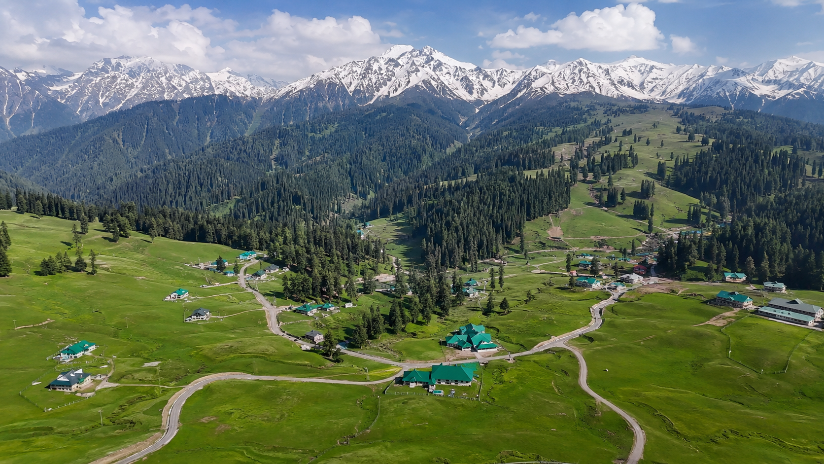 Gulmarg landscape with green meadows, forested slopes and snowy mountains